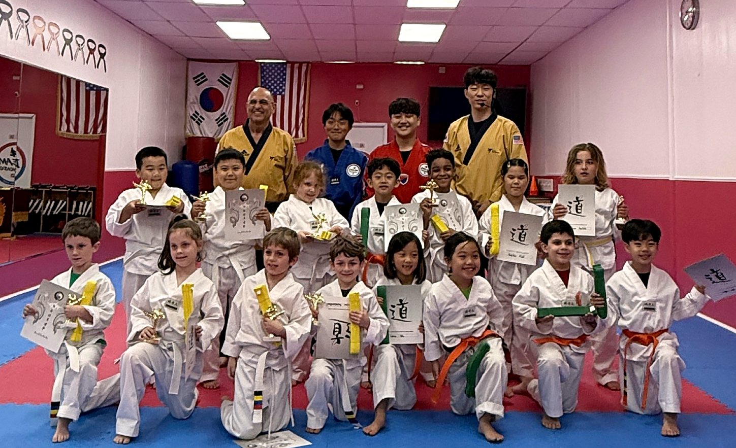 Young students holding new belts and certificates after a belt test